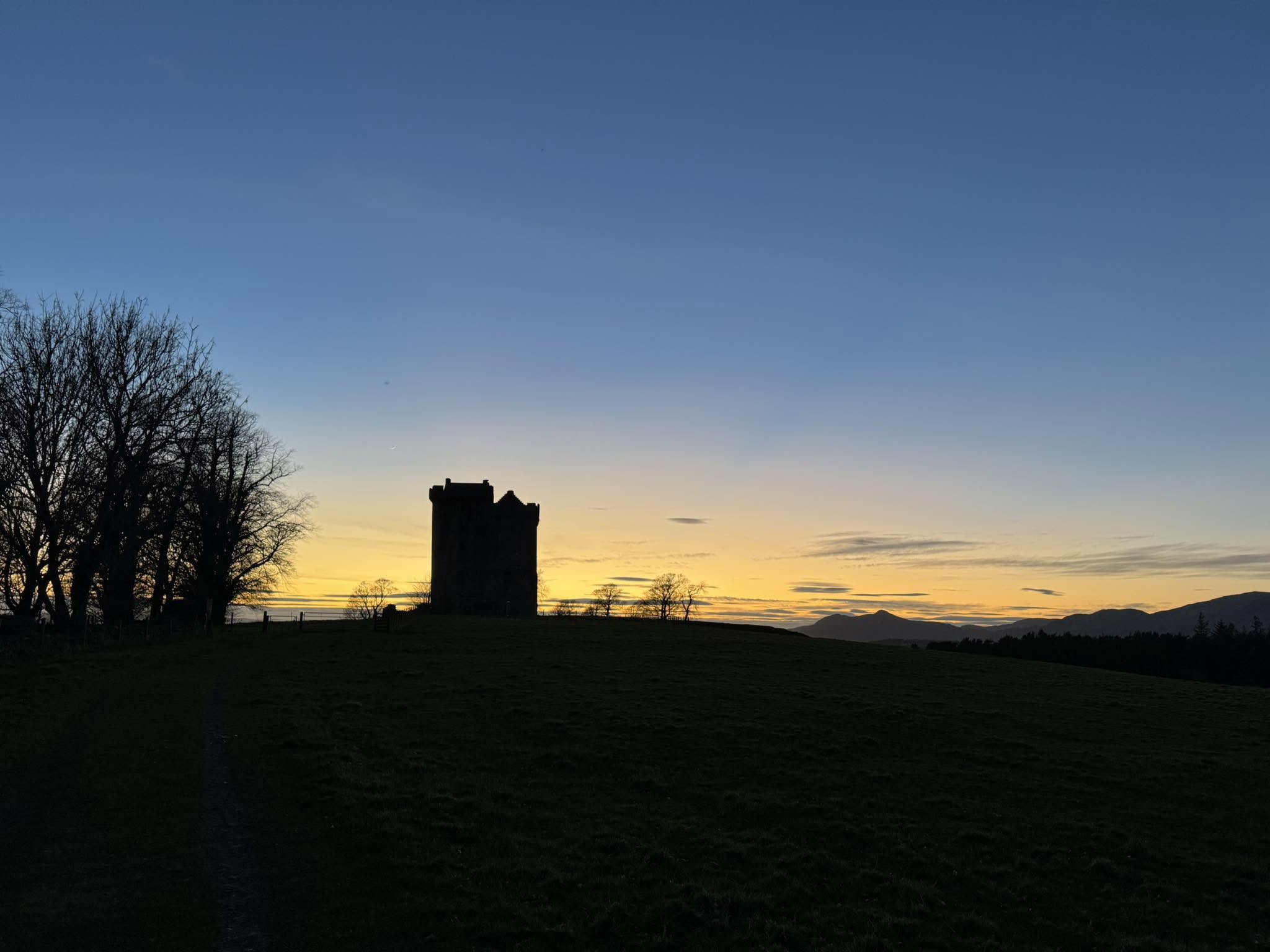 Silhouette of Clackmannan Tower at sunset with hills in the distance